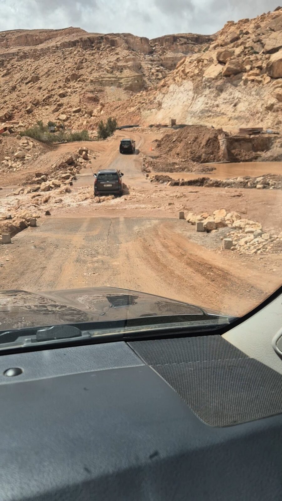 View through the windscreen of a convoy driving off-road through a rocky valley